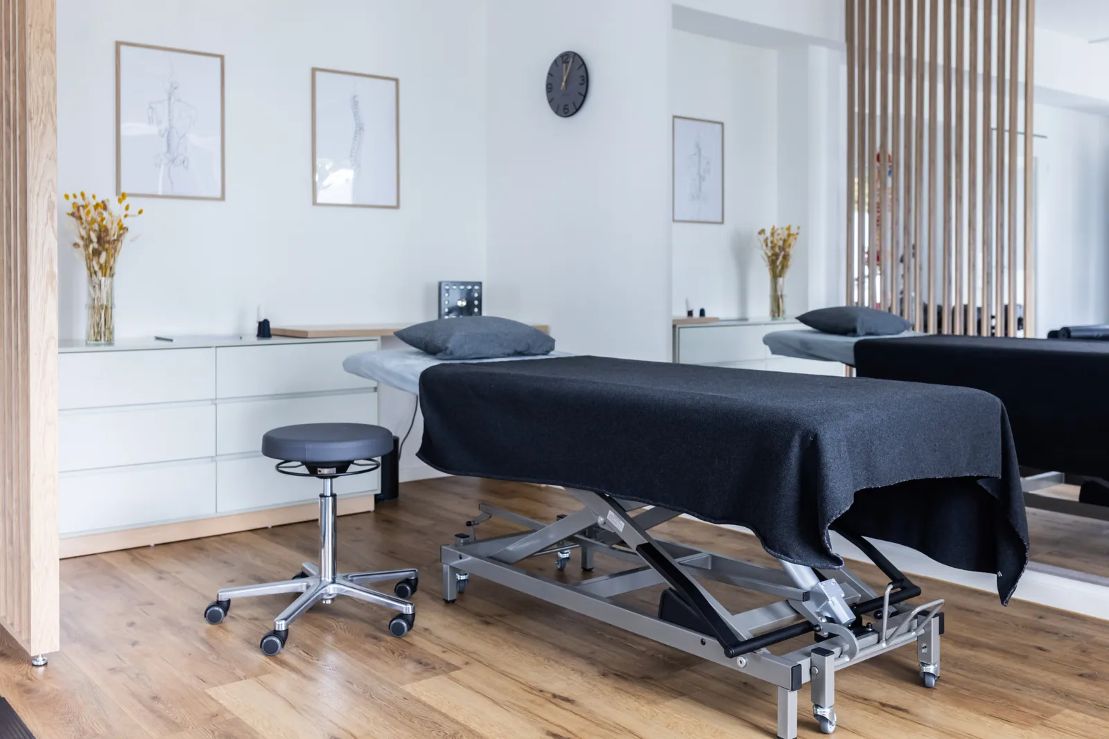 Behandlungsraum mit Therapieliege, Hocker und Holzlamellen