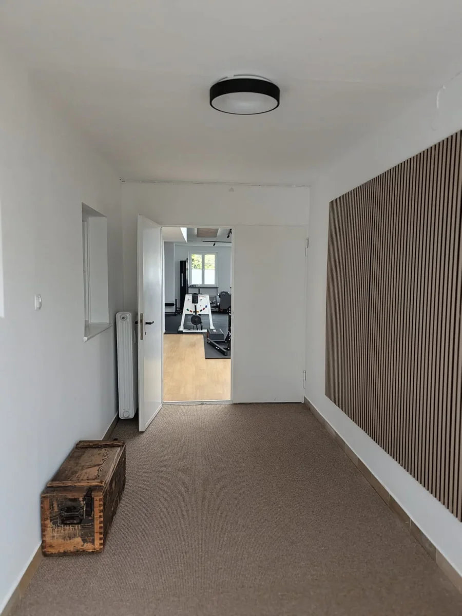 Flur mit Holzlamellenwand und Blick in den Trainingsraum