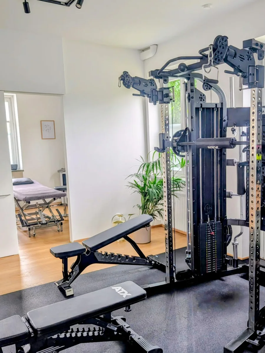 Trainingsbereich mit Kabelzug, durch die offene Tür der Behandlungsraum