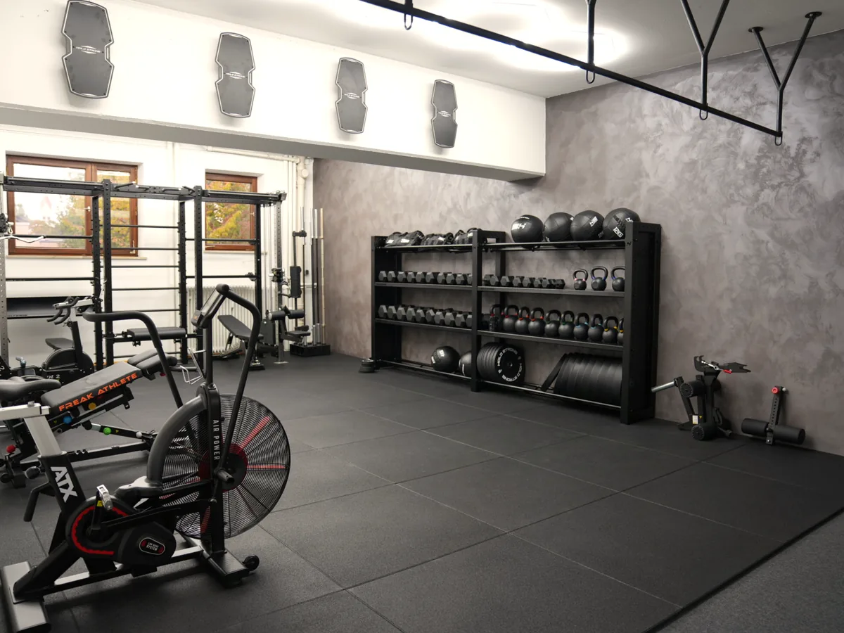 Trainingsraum mit Rack, Airbike, Rudergerät und Hantelregal