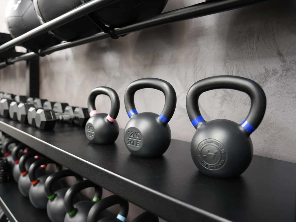 Drei Kettlebells auf einem Regal im Trainingsraum